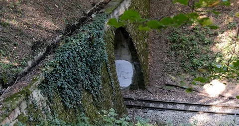 A steam train chugs through a tunnel in a mountainside Stock Footage 124926844