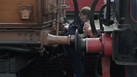 Steam train crewman manually coupling engine to carriage Stock Footage 299733569