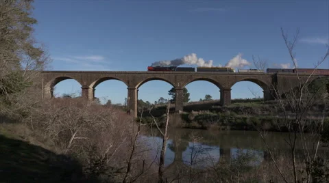 Steam train crossing a viaduct Stock Footage 64418568
