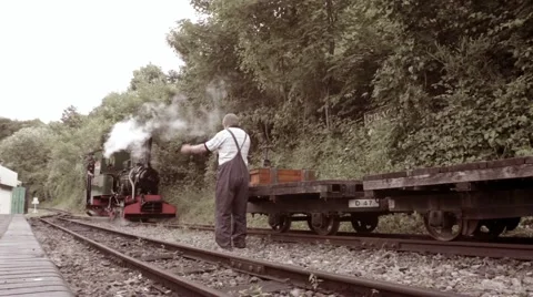 Steam train driver and his narrow gauge steam train arrive at station Stock Footage 64992402