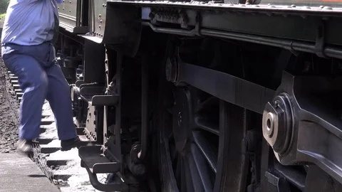 Steam Train driver climbs off a steam engine and walks past camera 4K Stock Footage 77417561