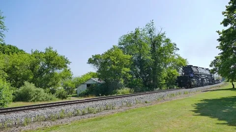 A steam train know as Big Boy moves along the tracks through a green landscape Stock Footage 340405373