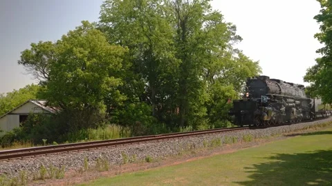 A steam train known as Big Boy travels along the tracks near green trees and Stock Footage 340405375