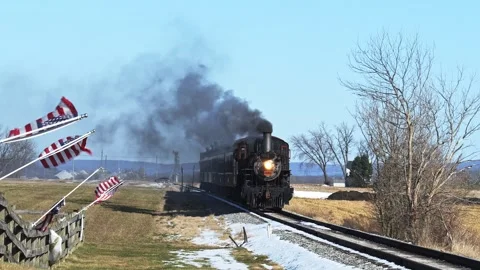 A steam train moves along the railway with smoke rising from its stack. The Stock Footage 325970913