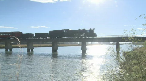 Steam train passes over bridge near sunset Stock Footage 636944