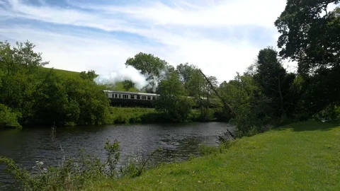 Steam train passing besides a river Stock Footage 76530276