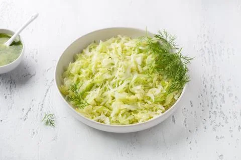 Steam white cabbage in a white ceramic bowl with herbs and green sauce Stock Photos