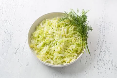 Steam white cabbage in a white ceramic bowl with herbs and green sauce Stock Photos