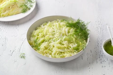 Steam white cabbage in a white ceramic bowl with herbs and green sauce Stock Photos