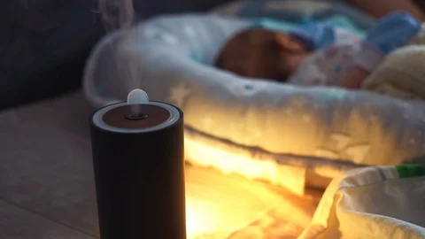 Steam from a working humidifier in front of sleeping baby. Black humidifier Vídeos de archivo 126667552