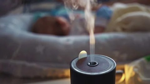Steam from a working humidifier in front of sleeping baby. Black humidifier Stock Footage 132517982
