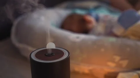 Steam from a working humidifier in front of sleeping baby. Black humidifier Stock Footage 135025721