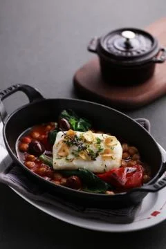 Steamed Atlantic cod saffron braised with bean on black stew Stock Photos