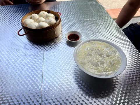 Steamed buns and egg drop soup on a metal table. Stock Photos