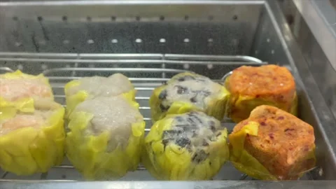 Steamed buns and various dim sum shumai inside a hot glass steamer showcase 库存影片 334949533