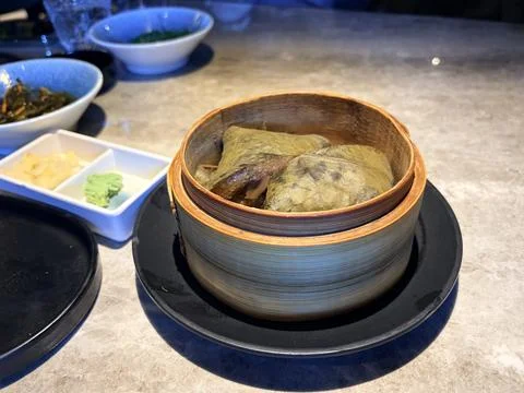 Steamed Leaf-Wrapped Dumplings in Bamboo Basket with Condiments Stock Photos
