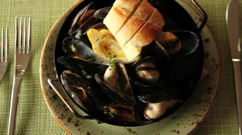 Steamed mussels dinner with bread, pan right and left Stock Footage 44604472
