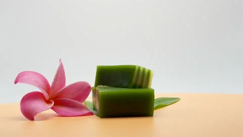 Steamed Pandan Layer Cake On Pandan Leaves Against White Background Rotated. Stockbeeldmateriaal 194989198