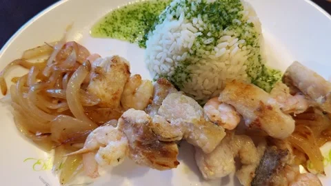 Steamed white fish served with caramelized onions and rice with basil sauce. Stock Footage 318230233