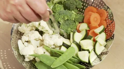 A steamer filled with vegetables being placed in a pot Stock Footage 24635573