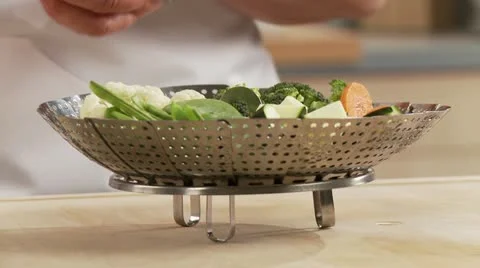 A steamer filled with vegetables being placed in a pot Stock-Footage 24635584