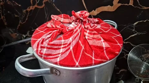 A steamer pot covered with a red and white checkered cloth tied at the top,.. Stock Footage 343230587
