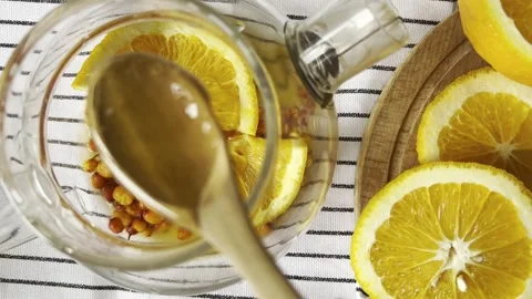 Steaming black tea infuser with honey, orange slices Stock Footage 304879599