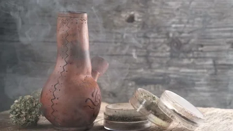 Steaming bong with cannabis on the table on which there is a grinder and a large Stock Footage 134941400