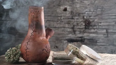 Steaming bong with cannabis on the table on which there is a grinder and a large Stock Footage 134941524