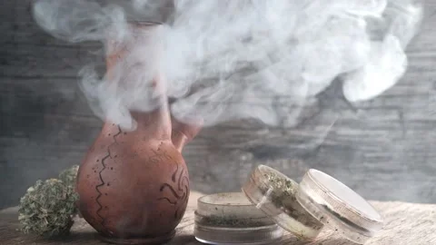Steaming bong with cannabis on the table on which there is a grinder and a large Stock Footage 134941975