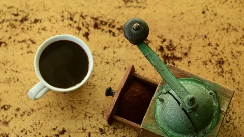 A steaming coffee cup and an old coffee grinder on a wooden surface Stock Footage 124500390