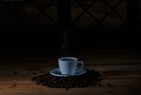 Steaming Coffee Cup on Roasted Beans with Dark Moody Background 스톡 사진