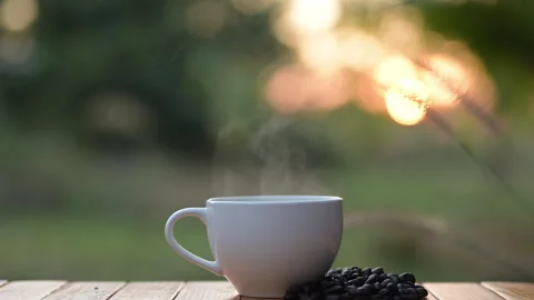 Steaming Coffee Cup Surrounded by Coffee Beans Outdoor Setting Natural Light Stock Footage 297192664
