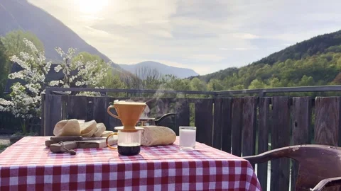 Steaming coffee with fresh bread and milk on rustic terrace with mountain view Stock Footage 333708320