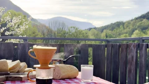 Steaming coffee with fresh bread and milk on rustic terrace with mountain view Stock Footage 333708344