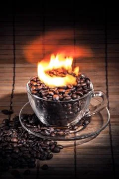Steaming cup of coffee on fire Stock Photos