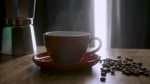 Steaming Cup of coffee or tea. A red cup of evaporating coffee on the table with Stock Footage 244608460