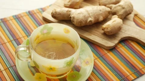 Steaming cup of fresh ginger tea and ginger roots on wooden board. Vídeo Stock 333030381