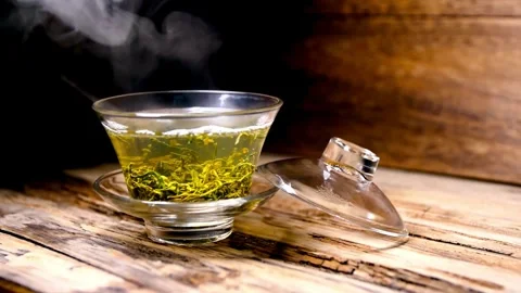 Steaming Cup of Green Tea with Lid on Wooden Surface 스톡 동영상 309543980