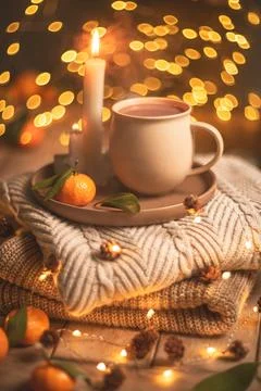 Steaming cup of hot beverage sits on a tray with a mandarin orange and lit .. Foto stock