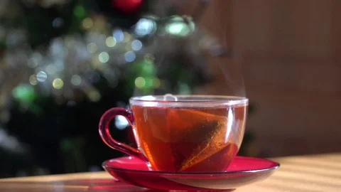 Steaming cup of hot tea with a Christmas tree on the background Stock Footage 83619783
