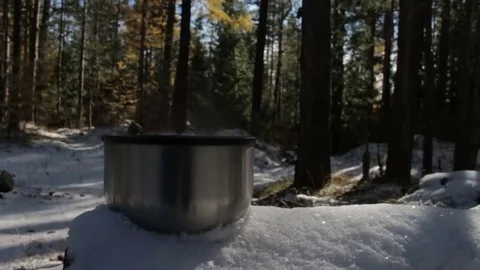 Steaming cup of hot tea or coffee standing on the snow in the forest. Stock Footage 69253916