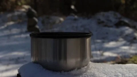 Steaming cup of hot tea or coffee standing on the snow in the forest. Stock Footage 69253933