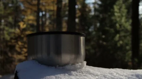 Steaming cup of hot tea or coffee standing on the snow in the forest. Stock Footage 69253993