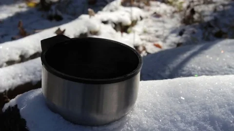 Steaming cup of hot tea or coffee standing on the snow in the forest. Stock Footage 69254063