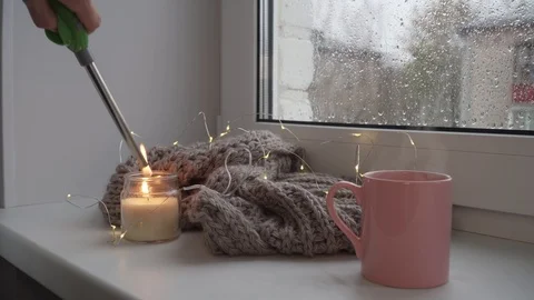 Steaming cup of tea and candle being lighten up on window sill Stock Footage 97498021