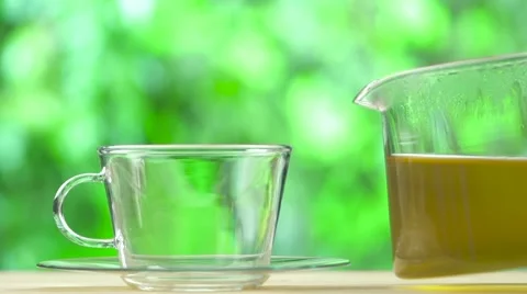 Steaming Cup of tea and teapot on blur green background Stock Footage 55912163