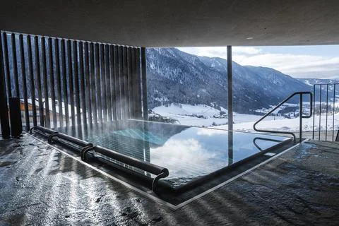 Steaming glass edged infinity pool with Dolomites winter peaks view Stock Photos