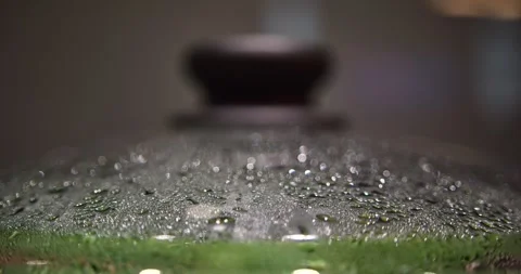 Steaming green beans beneath wet glass lid with black handle in soft focus Stock Footage 340277919