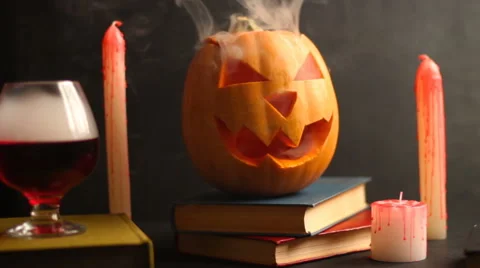 Steaming head Halloween Jack pumpkin on the table near a glass with smoke Stock Footage 68417018